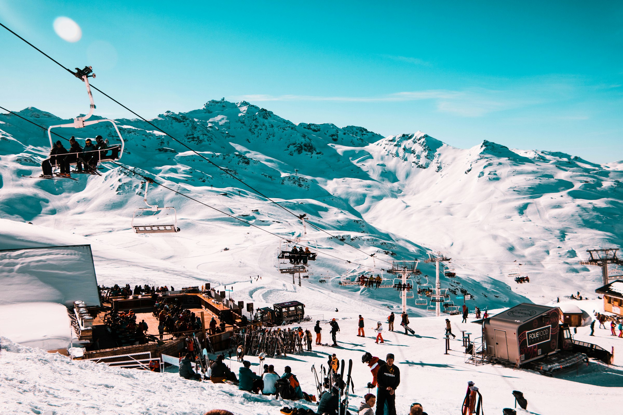 Tłum narciarzy przy La Folie Douce w Val Thorens: wyciągi krzesełkowe, taras, stoki i szczyty w pełnym słońcu